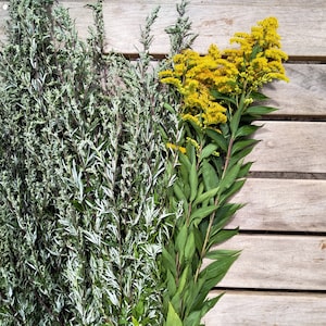 Pu&ograve; includere: Un mazzo di piante verdi a foglia con fiori gialli su una superficie di legno.