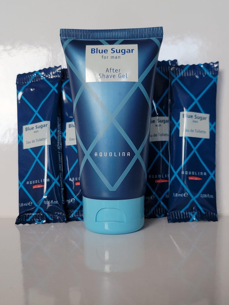 May include: A blue tube of "Blue Sugar for man After Shave Gel" with a light blue cap, surrounded by four small packets of "Blue Sugar man Eau de Toilette". The products have a geometric design and the brand name "AQUOLINA".