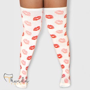 May include: White thigh-high socks with a repeating pattern of red and pink lips. The socks extend from the feet to mid-thigh. The brand name "Thunda Thighs" is visible at the bottom left.
