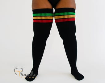May include: Black thigh-high socks with green, yellow, and red stripes at the top. The socks are made of a soft material and are designed to be worn over the knee. The socks are a bold fashion statement.