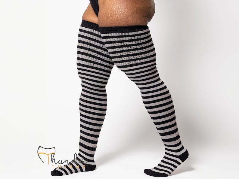 May include: Over-the-knee socks with alternating black and gray horizontal stripes. The socks have a black cuff at the top and black toes and heels. The socks are made of a soft, stretchy material.