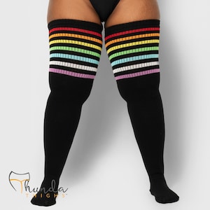 Könnte beinhalten: Schwarze Overknee-Socken mit Regenbogenstreifen am oberen Rand. Die Socken haben Streifen in Rot, Orange, Gelb, Grün, Blau, Weiß und Lila. Die Socken sind aus weichem, dehnbarem Material.