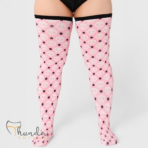 May include: Pink thigh-high stockings with a repeating pattern of white skulls and black stars. The top band is black. The stockings are made of a soft, stretchy material.