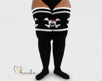 May include: Black thigh-high socks with white stripes at the top. The socks feature a white skull and crossbones design with a pink bow. The brand name "Thunda Thighs" is visible in the lower left corner.