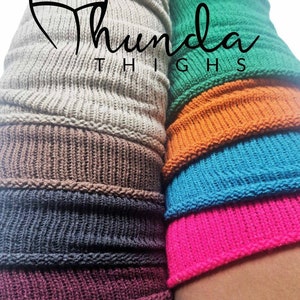 May include: Close-up of colorful knitted leg warmers in shades of gray, brown, navy, burgundy, green, orange, turquoise, and pink. The text "Thunda Thighs" is displayed in a stylized font.