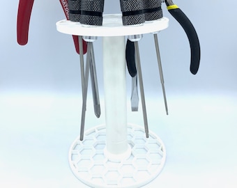 May include: A white plastic tool organizer with a hexagonal base and a central column. Seven tools are displayed in the organizer, including a pair of pliers, a red-handled screwdriver, and five screwdrivers with black handles.