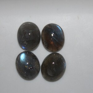 May include: Four oval-shaped labradorite gemstones with a dark gray base and iridescent blue and green flashes.