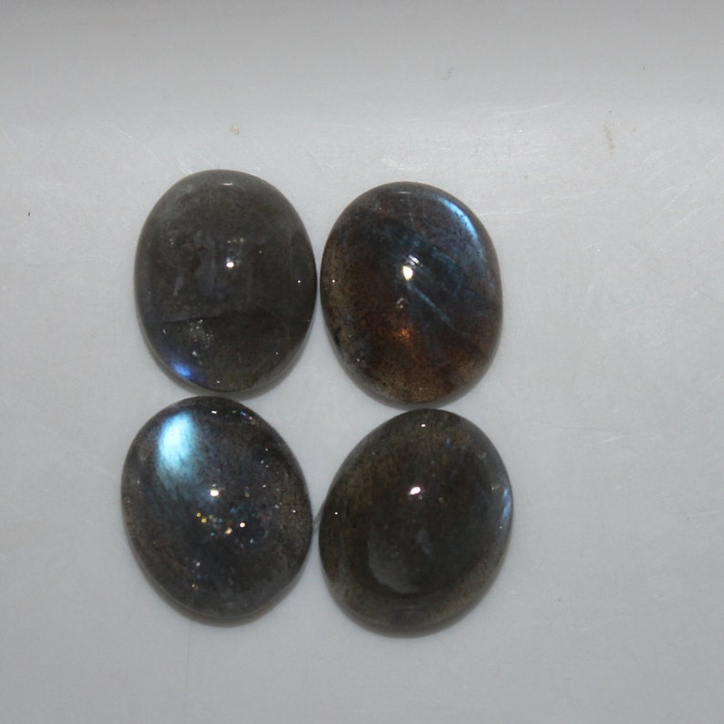 May include: Four oval-shaped labradorite gemstones with a dark gray base and iridescent blue and green flashes.