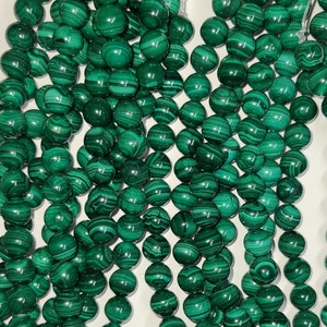 Peut inclure: Un collier de perles de malachite verte. Les perles sont rondes et ont une finition lisse et polie. Les perles sont enfilées sur une ficelle transparente.