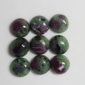 May include: Nine round green, pink, and black gemstone cabochons. The cabochons are polished and have a smooth, glossy finish.
