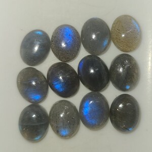May include: Twelve oval-shaped labradorite gemstones with iridescent blue and gray hues.