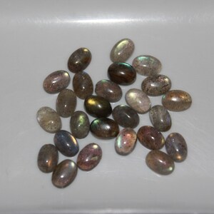 May include: A collection of oval-shaped labradorite gemstones in various shades of gray, green, and brown with iridescent flashes.