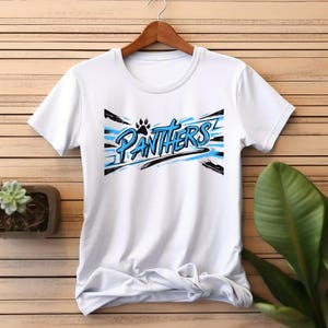 Puede incluir: Camiseta blanca con un dise&ntilde;o gr&aacute;fico azul y negro que dice "Panthers" con una huella de pata.