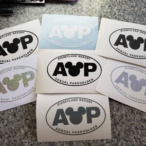 May include: Six white oval stickers with the text "Disneyland Resort Annual Passholder" and a stylized Mickey Mouse head with the letters "AUP" in black, gray, and silver.