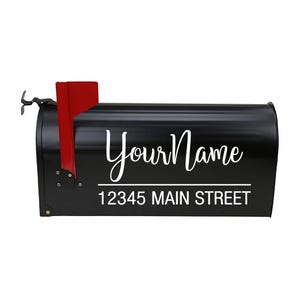May include: Black mailbox with white text that reads "Your Name" above "12345 MAIN STREET". The mailbox has a red flag on the side and a curved handle. The mailbox is made of metal.