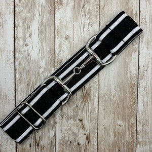 May include: Black and white striped fabric strap with a silver metal buckle. The strap is a popular accessory for bags and purses.