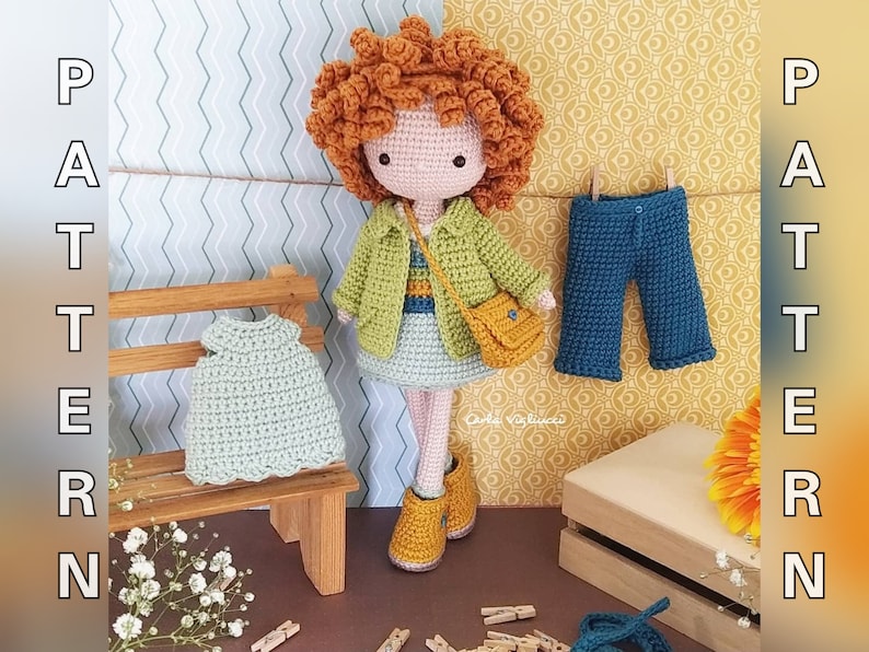 May include: A crocheted doll with brown curly hair wearing a green jacket, a yellow bag, and a blue and white dress. The doll is standing on a wooden bench with a green crocheted dress on it. The background is a patterned wall with the word "PATTERN" on either side.