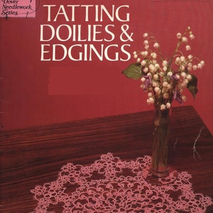 May include: A book titled "TATTING DOILIES & EDGINGS" from the Dover Needlework Series. The cover features a pink tatted doily on a dark wood surface with a vase of white flowers.