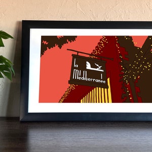 May include: A framed illustration of a restaurant sign with the text "La Mille Mediterranee" in a brown wooden frame with a red, yellow, and brown background. The sign is hanging from a building with string lights.