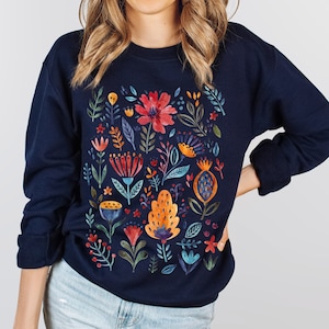 May include: A navy blue sweatshirt with a colorful floral pattern printed on the front. The flowers are in shades of red, orange, yellow, blue, and green.