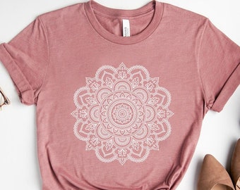 Puede incluir: Una camiseta color malva con un diseño de mandala blanco impreso en la parte delantera.