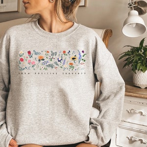 May include: Gray sweatshirt with a floral design and the text "Grow Positive Thoughts".