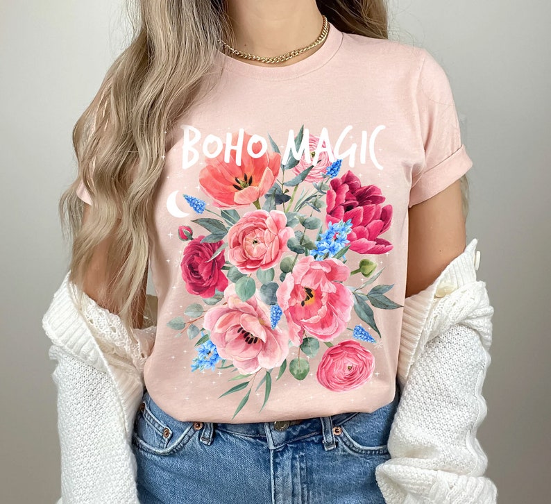 Może przedstawiać: R&oacute;żowy T-shirt z kwiatowym wzorem i napisem "BOHO MAGIC" białymi literami.