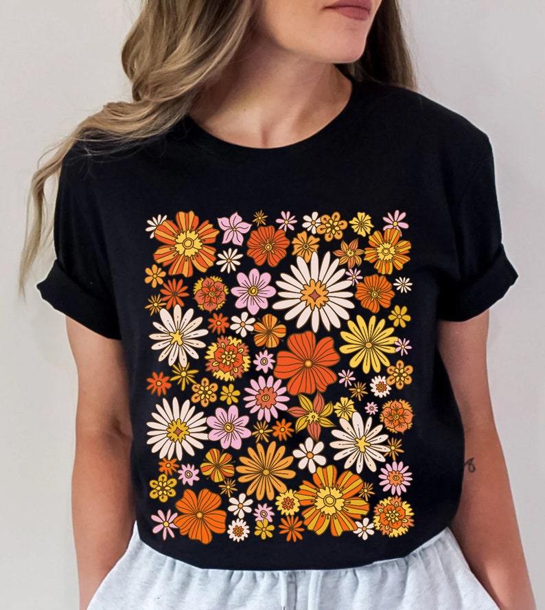 May include: Black t-shirt with a retro floral print featuring orange, yellow, pink, and white flowers.