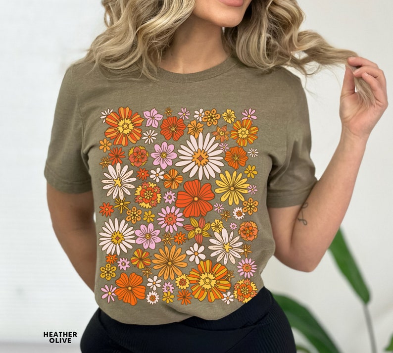 May include: A green t-shirt with a retro floral print featuring orange, yellow, pink, and white flowers.