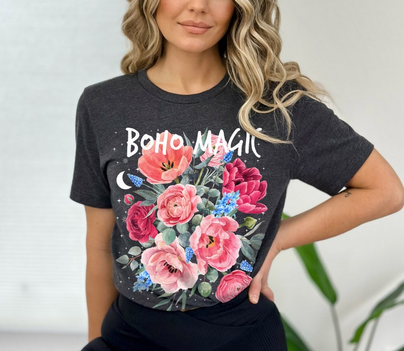 Może przedstawiać: Szary t-shirt z nadrukiem kwiatowym i napisem "boho magic" w kolorze białym. Kwiaty są r&oacute;żowe, czerwone i niebieskie.