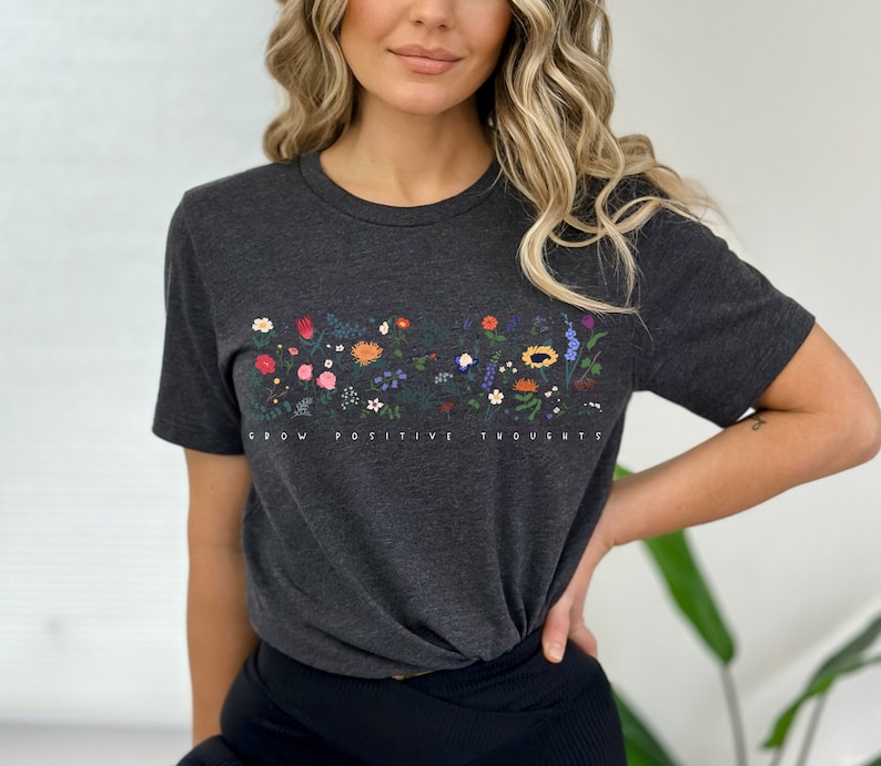 May include: A dark grey t-shirt with a floral design and the text "Grow Positive Thoughts".