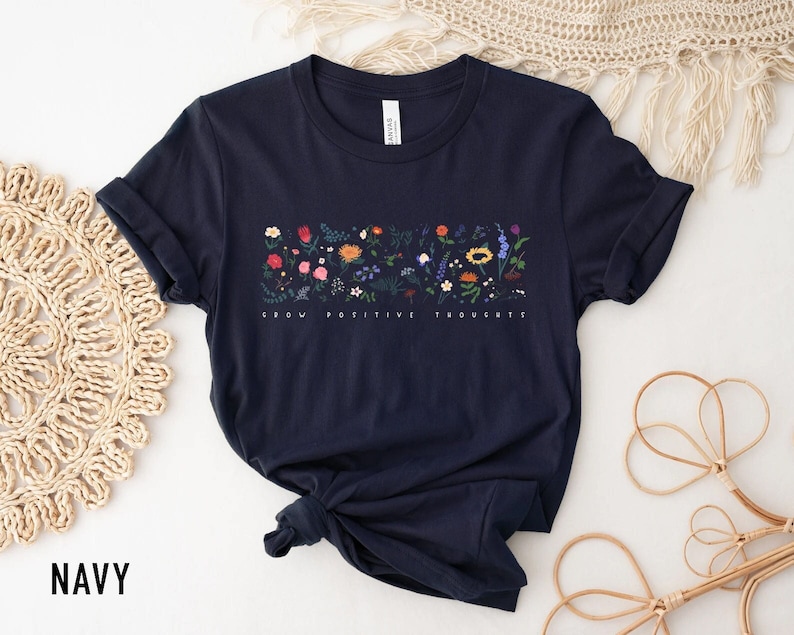 May include: Navy blue t-shirt with a floral design and the text "Grow Positive Thoughts".