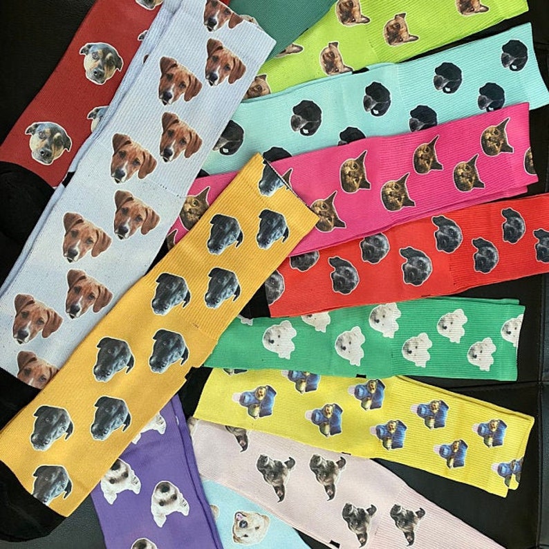 May include: A collection of colourful socks featuring various dog faces printed on them. The socks are arranged in a row, with the dog faces facing the viewer. The socks are made from a soft, comfortable material and are ideal for everyday wear.