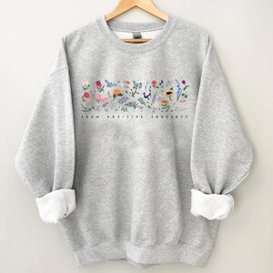 May include: Gray sweatshirt with a floral design and the text "Grow Positive Thoughts" printed on the front.