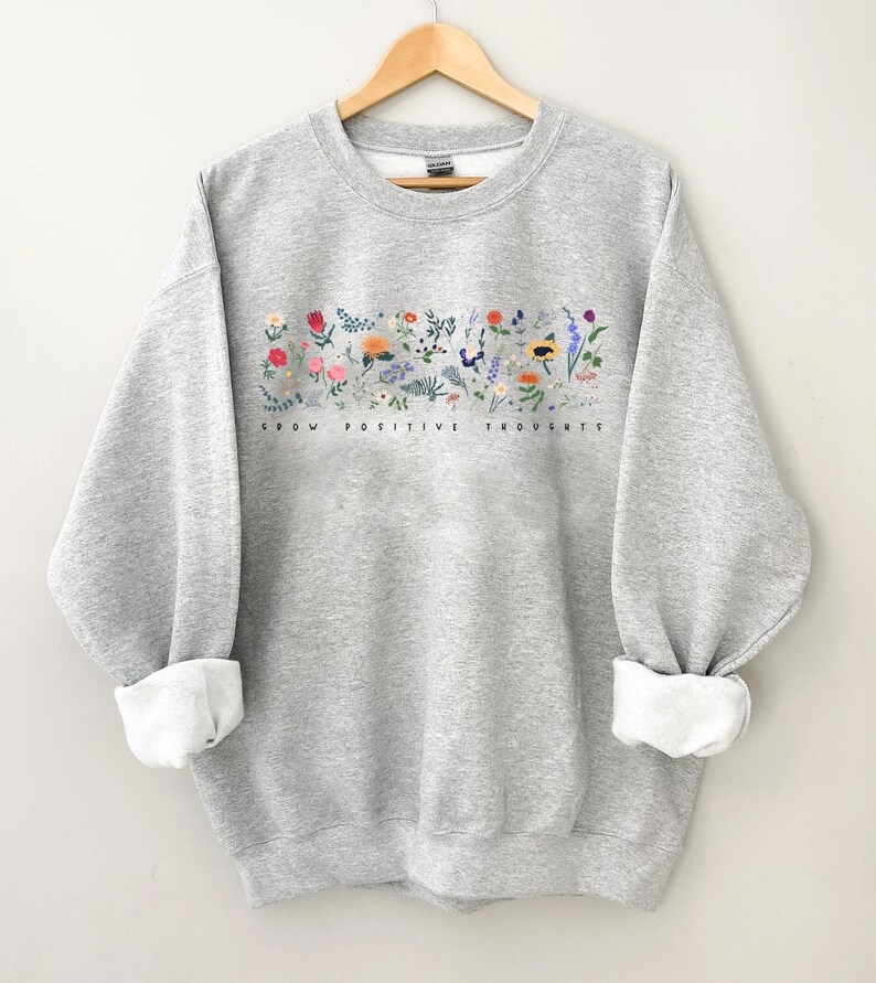 May include: Gray sweatshirt with a floral design and the text "Grow Positive Thoughts" printed on the front.
