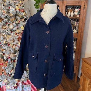 May include: A navy blue wool jacket with a button-up front and two large pockets. The jacket is on a mannequin and has a brown collar.