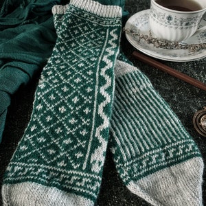 May include: A pair of knitted socks with a green and white geometric pattern. One sock has a striped pattern, while the other has a more intricate design.