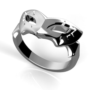 May include: A silver ring featuring a mask design. The mask is stylised and has a geometric pattern.