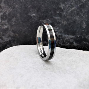May include: A silver ring with a black inlay. The inlay has a subtle iridescent sheen.