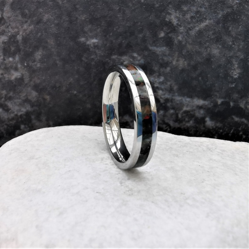 May include: A silver ring with a black inlay. The inlay has a subtle iridescent sheen.