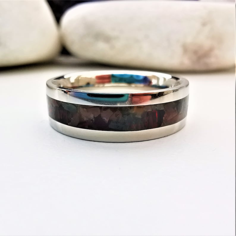May include: A silver band with a dark brown inlay of colorful, iridescent stones.