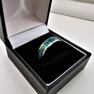 May include: A silver ring with a green and blue opal inlay. The ring is in a black ring box.