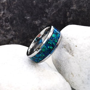 May include: A silver ring with a blue and green inlay. The ring is made of tungsten carbide and has a polished finish.