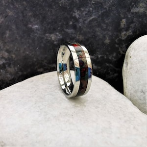 May include: A silver ring with a black and red inlay. The ring is polished and has a smooth finish.