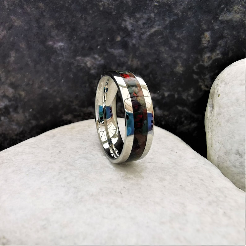 May include: A silver ring with a black and red inlay. The ring is polished and has a smooth finish.