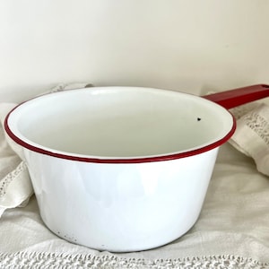 Peut inclure: Une casserole en émail blanc avec un bord rouge et une poignée rouge.