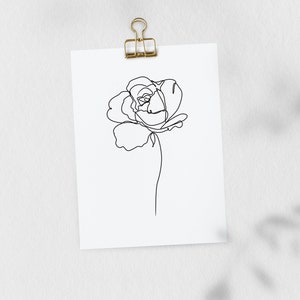 May include: A black and white line drawing of a single rose on a white background. The drawing is attached to a white wall with a gold binder clip.