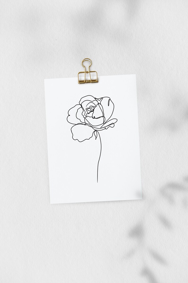 May include: A black and white line drawing of a single rose on a white background. The drawing is attached to a white wall with a gold binder clip.