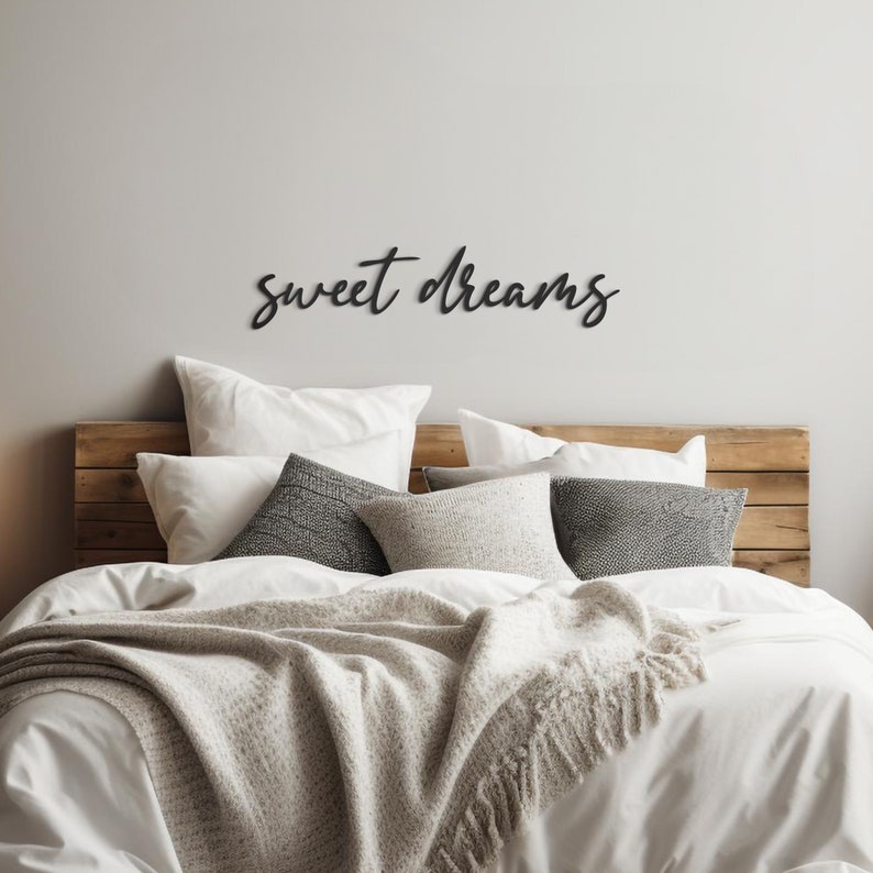 May include: A white bed with a wooden headboard and a white blanket. The headboard has a black wooden sign that says "sweet dreams".