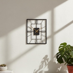 Peut inclure: Une horloge murale rectangulaire en métal noir avec des aiguilles dorées et des chiffres romains. L'horloge a un design géométrique et est fixée sur un mur blanc. Ses dimensions sont d'environ 30 cm sur 30 cm.
